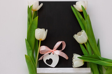 Black chalk board mockup with tulip flowers on white background. Blackboard menu with easel, spring sales. Copy space frame ad text content. Blank inscription template. Education advertisement display