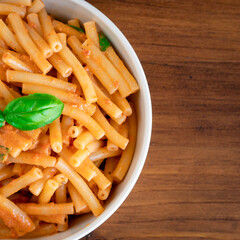 Healthy organic Italian macaroni homemade fresh pasta spaghetti noodles cook with basil tomato garlic pepper sauce with vegan vegetarian recipe in white bowl on wooden vintage table