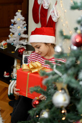 Cute little children Santa hats with Christmas gift boxes at home.