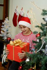 Cute little children Santa hats with Christmas gift boxes at home.