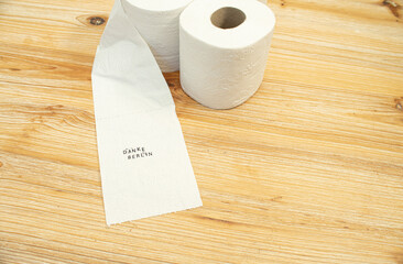 Toilettenpapier auf Holztisch mit Statement auf deutsch zu Berliner Entscheidung Entschluss