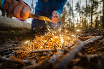 Man outdoors makeing fire by flint. View from above. Flying sparks.