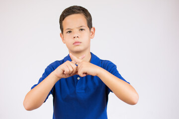 Young handsome little boy wearing casual clothes standing over isolated background. Has rejection angry expression crossing fingers doing refusal negative sign.