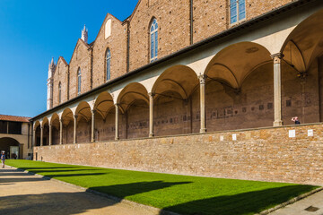 Great view of the first cloister in the Basilica di Santa Croce in Florence, Italy on a sunny day. Under the long porch with cross vaults are funeral monuments.