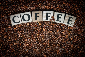 Single word Coffee, made of wooden blocks on Background with roasted coffee beans.