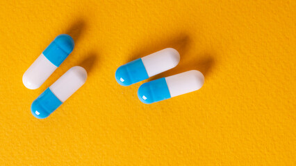white and blue pills on yellow background