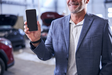 Bearded man holding modern smartphone and smiling