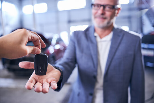 Male Hand Giving Smart Car Key To Driver At Service Station