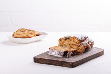 Traditional Christmas stollen cake on white background. Fruit bread with nuts, spices and dried fruit. Copy space.