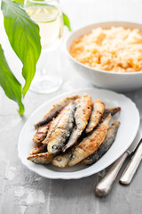 fried small sardines with tomato rice on white dish on ceramic