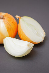 Two unpeeled whole and half raw yellow onions on black surface. Flat lay. Copy space