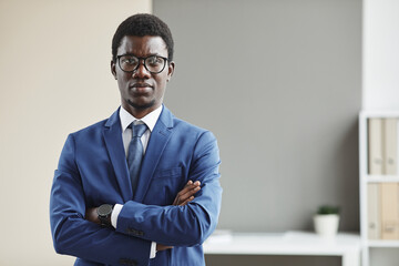 Portrait of African young businessman in eyeglasses and in formalwear standing with his arms crossed and looking at camera