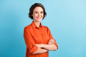 Photo of pretty attractive lady bobbed hairdo arms crossed self-confident person worker friendly smile white teeth good mood wear orange office shirt isolated blue color background - obrazy, fototapety, plakaty