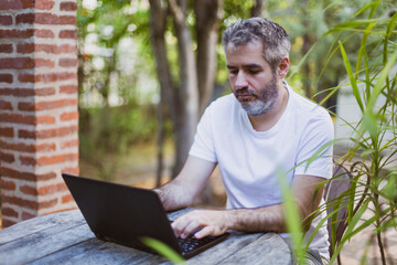 Remote work concept.A man works with a laptop in the garden.