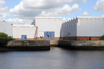 Obraz premium River View with Large White Industrial Buildings on Sunny Day