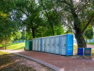 Portable washrooms in nature. Long row of portable bio toilet cabins in Moscow park. Line of...