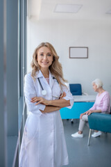 Obraz premium Long-haired blonde doctor standing with arms crossed