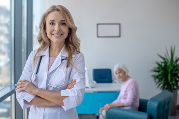 Long-haired blonde doctor standing with arms crossed and smiling