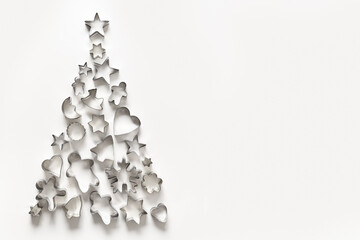 Christmas-themed cookie cutters for gingerbread in shape of Xmas tree on white background.Top view,...