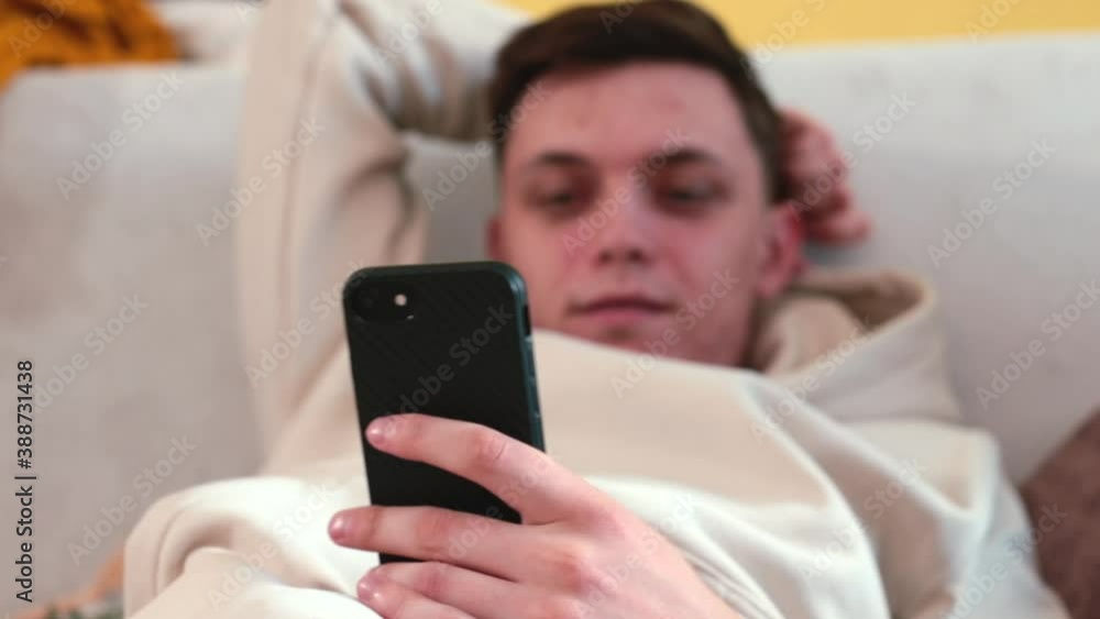 Poster using the phone in the hands of a guy sitting on the couch. checking notifications on your smartphon