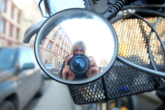 Travel concept city tourist photographer taking self photo in the mirror of bicycle in the street of city Saint-Petersburg