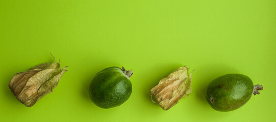 Feijoa and physalis, against a green background, selective focus. Healthy eating. Diet. Copy space. Banner.