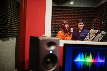 Fototapeta na wymiar Young asian duet singers with microphone recording song in record music studio.