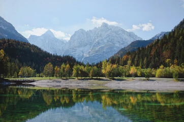 Fototapeta na wymiar Beautiful view on green lake in the mountains against the colorful autumn forest in slovenian alps at Lake Jasna. 