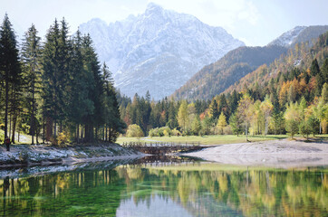 Beautiful view on green lake in the mountains against the colorful autumn forest in slovenian alps. 