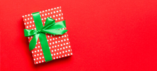 Obraz premium Top view Christmas present box with green bow on red background with copy space