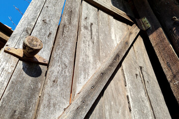 Rusty iron handle on old wooden door of abandoned village house.