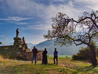 A priest and two faithful praying in front of the Pindreau monument, place of the Marian apparition of Our Lady of Laus. South of France. Notre Dame du Laus.
