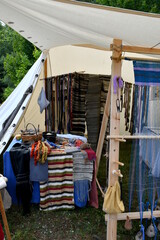 A view of a cloth tent with the display of handmade knitting goods and knitting accsories on wooden racks and wooden tables seen on a sunny summer day in Poland during a history fair