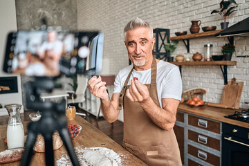 Happy adult male chef featuring raspberries and blueberries and filming a vlog video