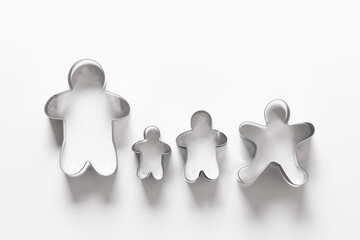 Four Christmas-themed cookie cutters in shape of gingerbread man isolated on white background....