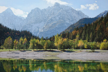 Fototapeta na wymiar Autumn alps mountains in day light reflected in calm waters of lake.
