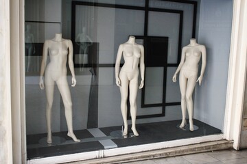 The window of empty clothing store in the commercial center of Athens, with mannequin dolls in the...