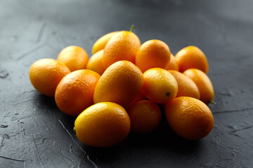 Kumquat, fresh citrus fruits on black table. Tropical fruits