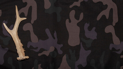 Hunting background. On camouflage background flat lay with hunting accessories. Top view with place...