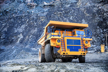 Big yellow quarry truck moves in the quarry for ore extraction