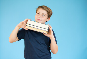 Education is funny and easy concept. Happy smiling little boy kid is holding in his hands many books. Free space for text and logo on blue t-shirt