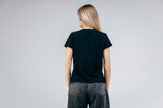 Back of stylish blonde girl wearing black t-shirt posing in studio
