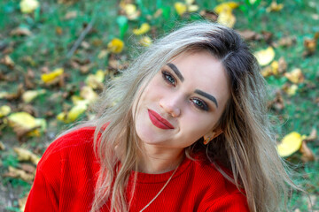 Naklejka premium smiling girl in red sweater, portrait