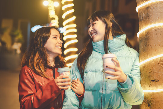Happy friends walking in city while drinking coffee - Young girls having fun sharing time together outdoor - Friendship and youth people lifestyle concept - Powered by Adobe