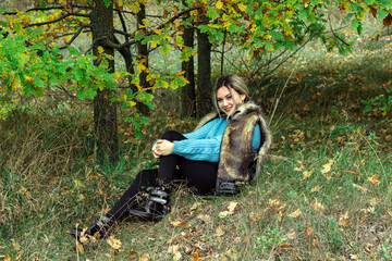 girl in a blue sweater sits under a tree, autumn time
