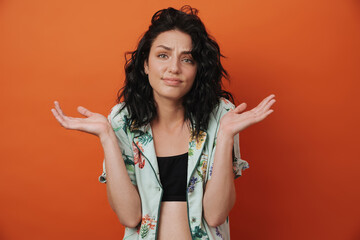 Confused woman isolated over orange wall background