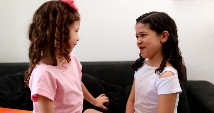 Children friends interacting with each other at home, two mix race siblings talking to each other