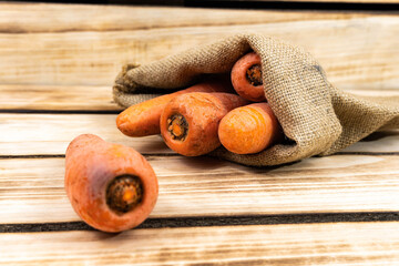 Carrots in an old bag on a wooden background. F