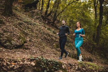 couple running and walking with bottles of water in the woods in autumn