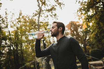 couple running and walking with bottles of water in the woods in autumn